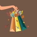 The symbolism of shopping during the autumn, a womans hand holds elegant packages with tree leaves Royalty Free Stock Photo