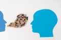 Two paper-cut heads facing each other, with streams of mixed letters flowing from one mouth Royalty Free Stock Photo