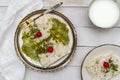 Traditional Turkish milky Ramadan Dessert named Gullac on vintage metal plate and white wooden background.