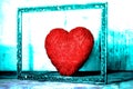 A red heart of passion in an old forgotten frame in an attic Royalty Free Stock Photo