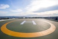 Symbols for helicopter parking on the roof of an office building. Empty square front of city skyline.