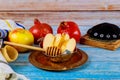 Symbols of the Jewish New Year with a shofar, honey jar, fresh apples pomegranates on Rosh Hashanah