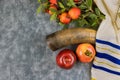 Symbols of the Jewish New Year with a shofar, honey jar, fresh apples pomegranates on Rosh Hashanah
