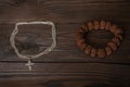 Symbols of religions, a Christian Orthodox cross on a chain around the neck and a Buddhist bracelet lie together on a wooden table Royalty Free Stock Photo