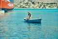 Symi, Greece- July 05 2017: Mature man in shabby vessel raises anchor in the sea near a huge ferry Royalty Free Stock Photo