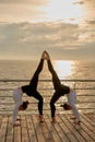 Symmetrical element in gymnastics. Sporty couple doing acroyoga, fitness or pilates practice in pair in morning sea Royalty Free Stock Photo