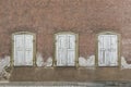 Symmetrical facade of abandoned, dilapidated house with 3 windows with shutters Royalty Free Stock Photo