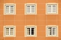 Symmetrical facade of an orange building with six white-framed windows. Royalty Free Stock Photo