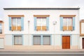 symmetrical facade of white spanish house with blue trimmed windows Royalty Free Stock Photo