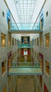 Symmetrical interior atrium of Royal Armouries Museum with glass ceiling under sunlight