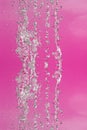 Symmetrical pattern of stopped water droplets with transparent streams on a pink background. Clash, opposition and mystical