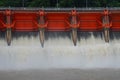 Symmetrical view of red dam gates controlling river flood discharge Royalty Free Stock Photo