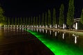 Symmetrically arranged trees with lanterns along the fountain in the Park of Krasnodar. Decorative pool or fountain with colored