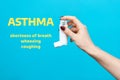 Symptoms of asthma. A woman`s hand holds an inhaler with medicine. Side view. Blue background with text