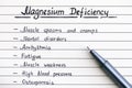 Symptoms of Magnesium Deficiency writing on the list with pen.