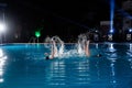 Synchronised swimming at night in pool. Royalty Free Stock Photo