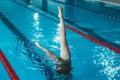 Synchronized swimming athlete trains alone in the swimming pool. Training in the water upside down. Legs peek out of the water.