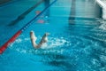 Synchronized swimming athlete trains alone in the swimming pool. Training in the water upside down. Legs peek out of the water.