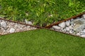 syntetic grass and real grass separated by iron and white rocks.. Royalty Free Stock Photo