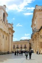 Syracuse, Italy - Apr 10th 2019: Vertical picture of tourists walking to the Piazza Duomo Square along beautiful Roman Catholic