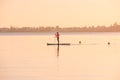 Syracuse, Italy / December 2018: Stand up Surf girl with paddle in a sunset ocean sea