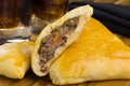 Syrian-Lebanese pie stuffed with meat called sfiha with one open in a cutting board in black background close