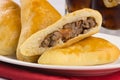 Syrian-Lebanese pie stuffed with meat called sfiha with one open in a platter in white background close