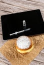 Syringe and an ampoule of insulin on the tablet, next to a Brazilian cream doughnuts