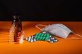 Syringe, ampoules of pills and a medical mask are illuminated lie on the table