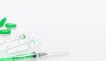 Syringe, ampules and green pills on white background. Medical treatment and vaccination concept. Copy space