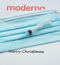 Syringe on a blue facemask withe the moderna logo