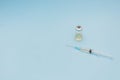 A syringe and a can of vaccine stand on a blue background, minimalism
