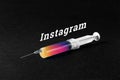 Syringe on a dark background and the word instagram. The concept of mania, Internet addiction