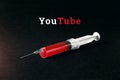 Syringe on a dark background and the word YouTube. The concept of internet addiction Royalty Free Stock Photo