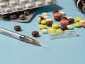 syringe and different of medicines, medicines, pills and vitamins are laid out on a blue background.