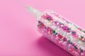 Syringe filled with colorful nano balls on a pink background Royalty Free Stock Photo