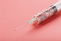 Syringe filled with colorful nano balls on a pink background