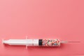 Syringe filled with colorful nano balls on a pink background Royalty Free Stock Photo