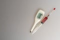 syringe filled with red liquid and electronic thermometer