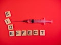 Syringe filled with solution. Words side effect on colored red paper texture background. Concept. Concern of vaccine shot side Royalty Free Stock Photo
