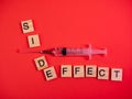 Syringe filled with solution. Words side effect on colored red paper texture background. Concept. Concern of vaccine shot side Royalty Free Stock Photo
