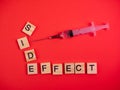 Syringe filled with solution. Words side effect on colored red paper texture background. Concept. Concern of vaccine shot side Royalty Free Stock Photo
