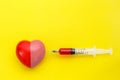 Syringe give medicine to red heart shape on yellow background. U