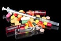 Syringe with glass vials and medicinal tablets and pills on black background. Assorted medical drugs