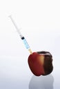 Syringe injecting a rotten apple. Conceptual image