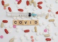 Syringe With the inscription covid-19 and various colored tablets next to it