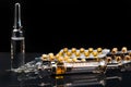 Syringe with medication, medical ampoules and blister packs with pills on black background Royalty Free Stock Photo