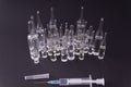 Syringe with medicine in front of ampoules on a black background