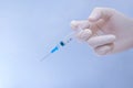 syringe with 0.5 ml of medication in the hand of a doctor on a blue background