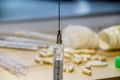 A syringe with a needle on the background of medicines and a wooden table